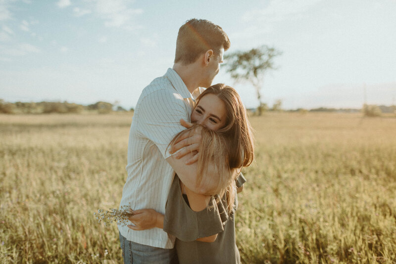 couple hugging in field at sunset