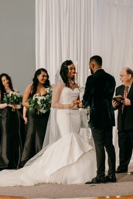 Real bride wearing a custom bridal veil while placing the ring on her groom's finger.