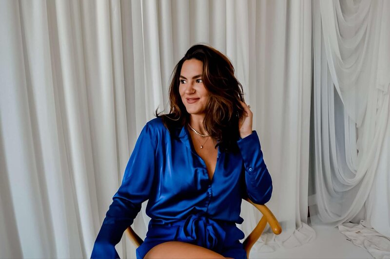 Portrait of Emily Michele in a blue satin blouse, symbolizing grounded elegance, self-expression, and embodied confidence for her Unveiled coaching program.
