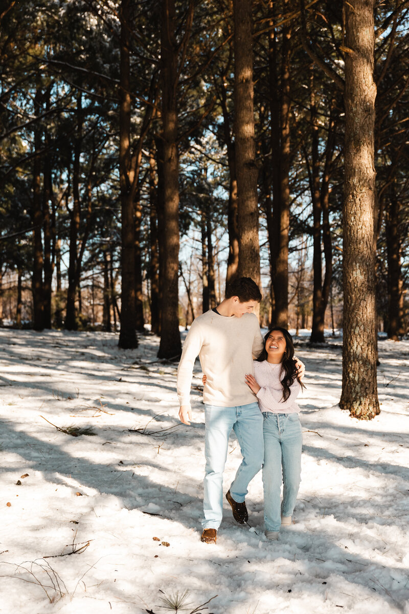 Couple captured in the woods during winter, with bare trees creating a serene, intimate atmosphere, showcasing their love in a quiet setting.