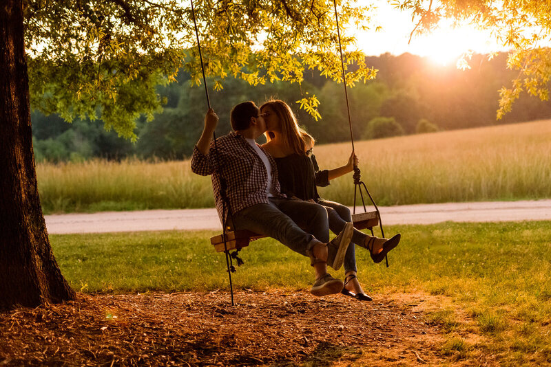 Couple kisses on a tree swing at The Meadows Raleigh wedding venue