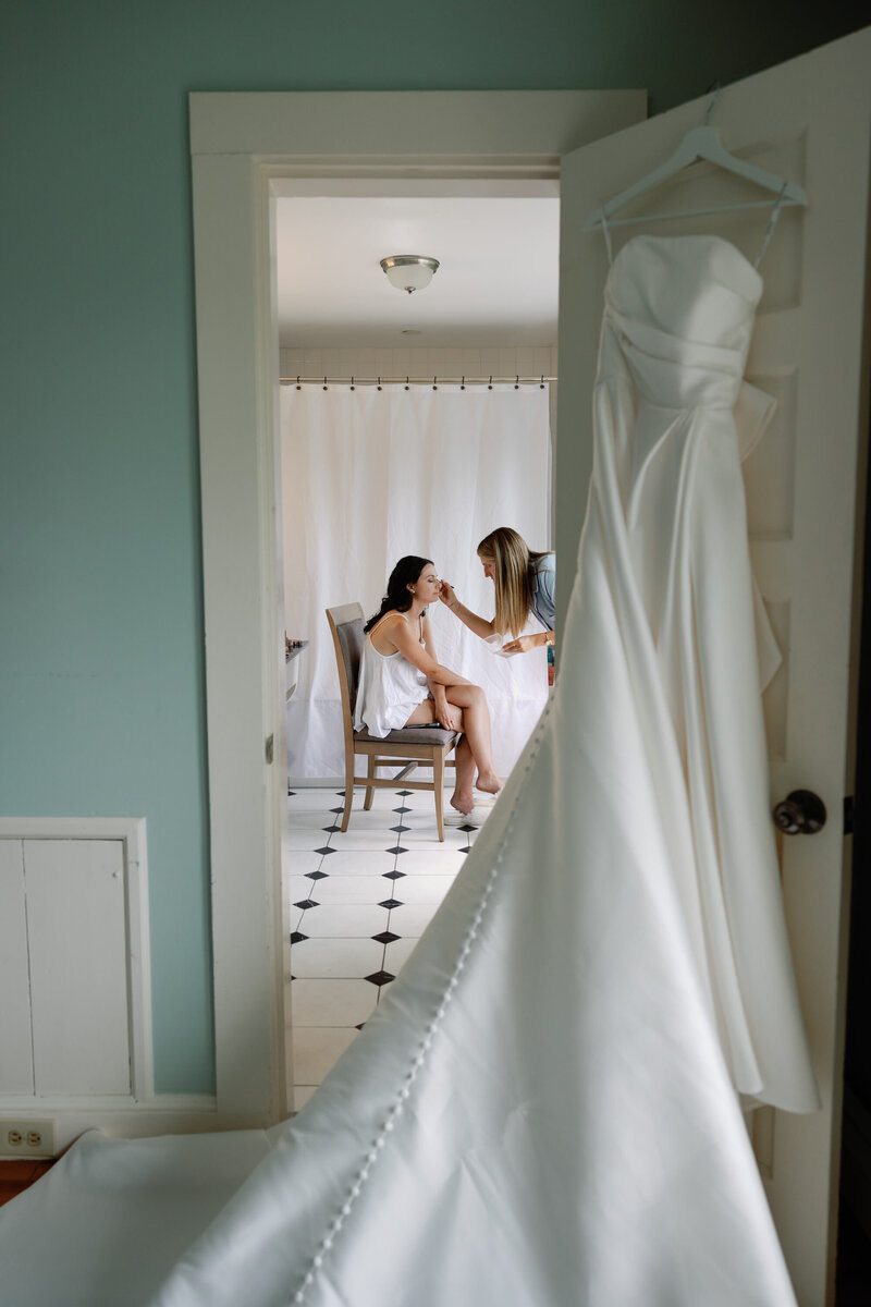 Looking in through doorway on a bride getting her make up done before her wedding