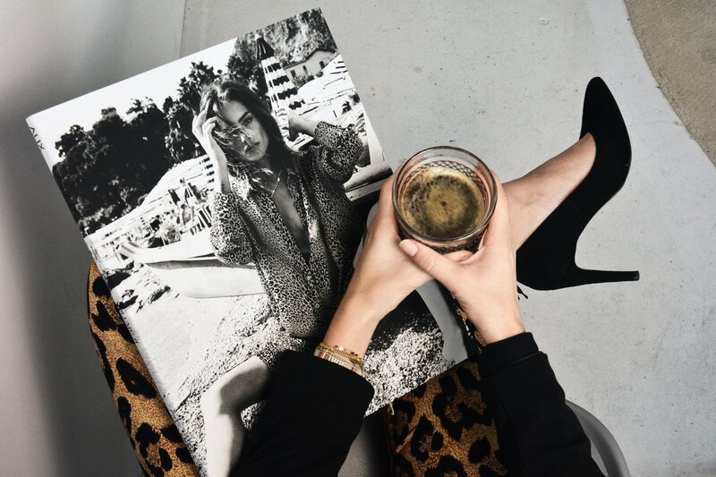 woman holding coffee with magazine and leopard clothing