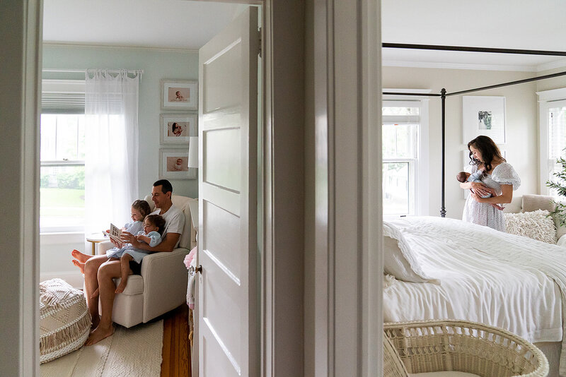 Family taking care of kids in two rooms with mom holding newborn and dad reading to two toddlers
