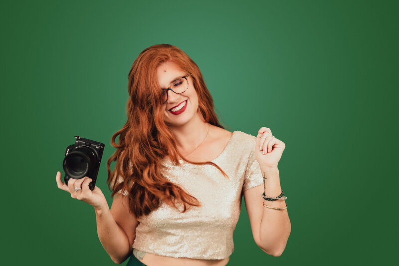 Meagan McGregor holding her camera and swaying her hair around with a big smile on her face