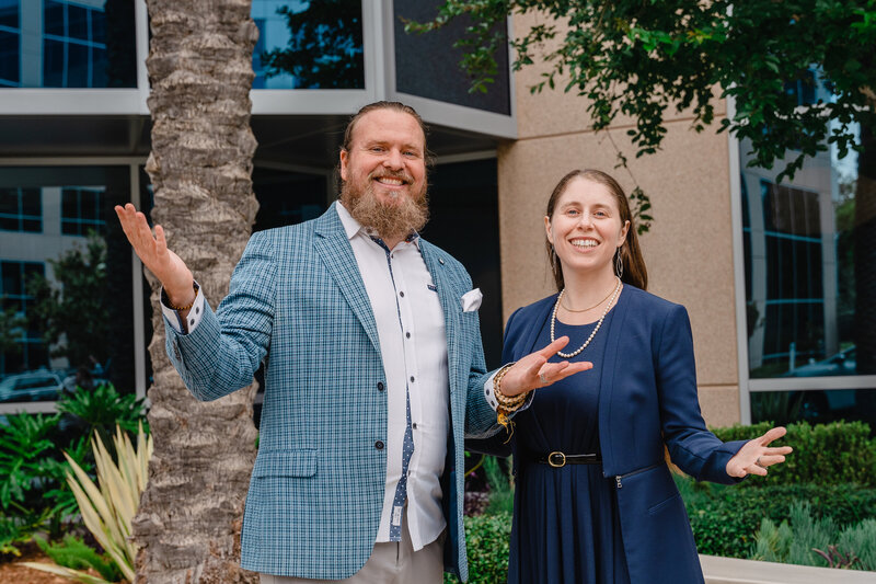 Co-Founders of NKB Consultancy, Jarrett and Rebecca standing outside with their arms out