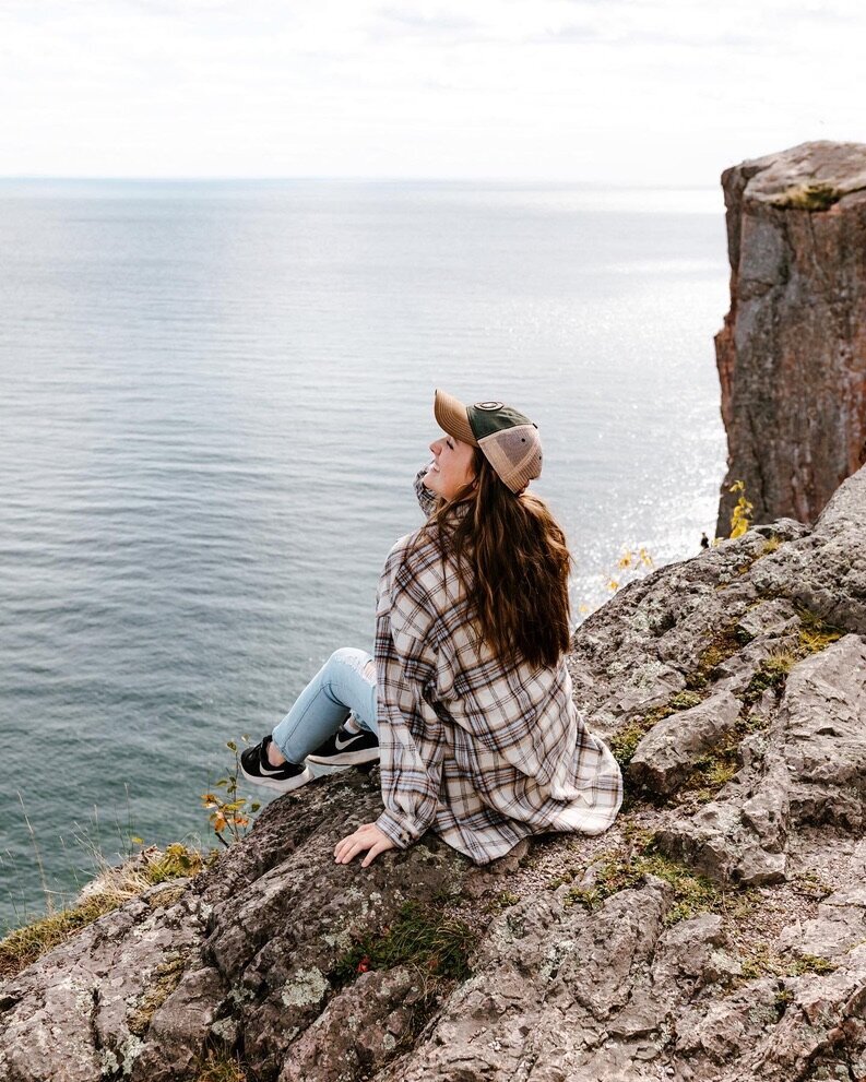 Samantha sitting on a rocky ledge looking out into the ocean