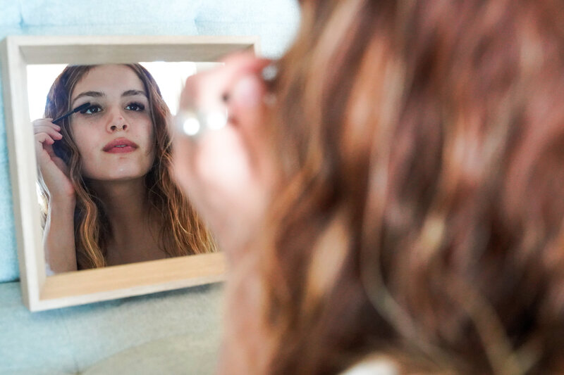 Woman looking in mirror brushing lashes