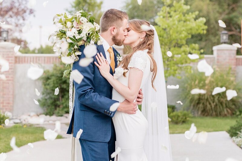 Couple kissing surrounded by flower petals at Talia Event Center