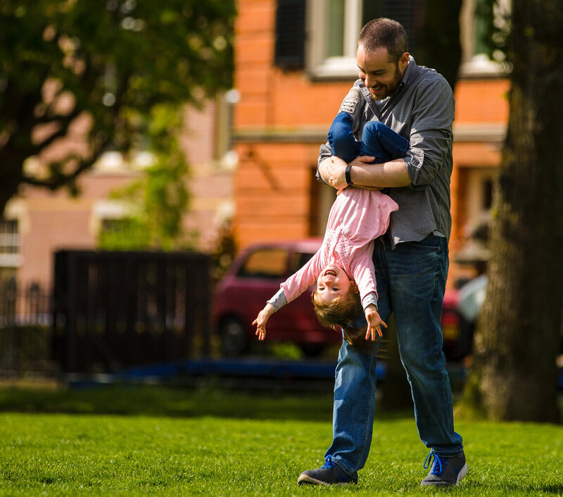 A man holding a child upside down in a park.