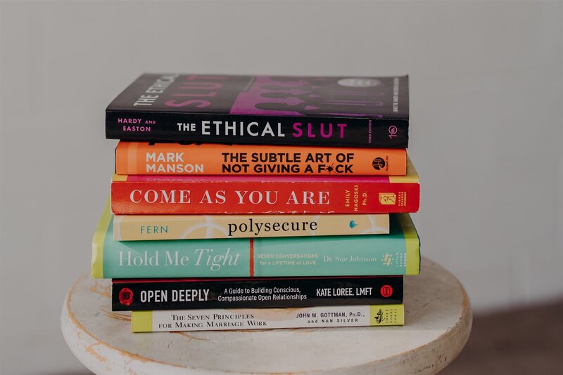 woman smiling while holding 'the ethical slut' book against her chest