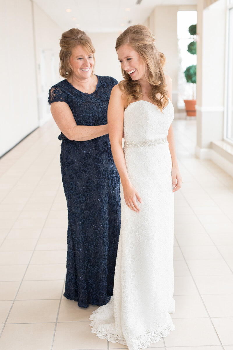 Mother buttoning daughter's wedding dress
