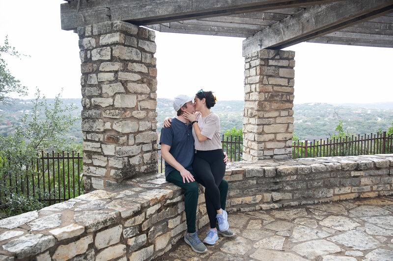 An intimate moment captured by an Austin wedding photographer, showcasing a couple's passionate kiss against a rustic stone wall.