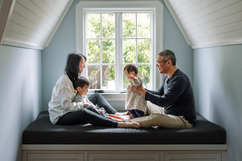 family of four sitting together in a window seat playing and interacting with each other