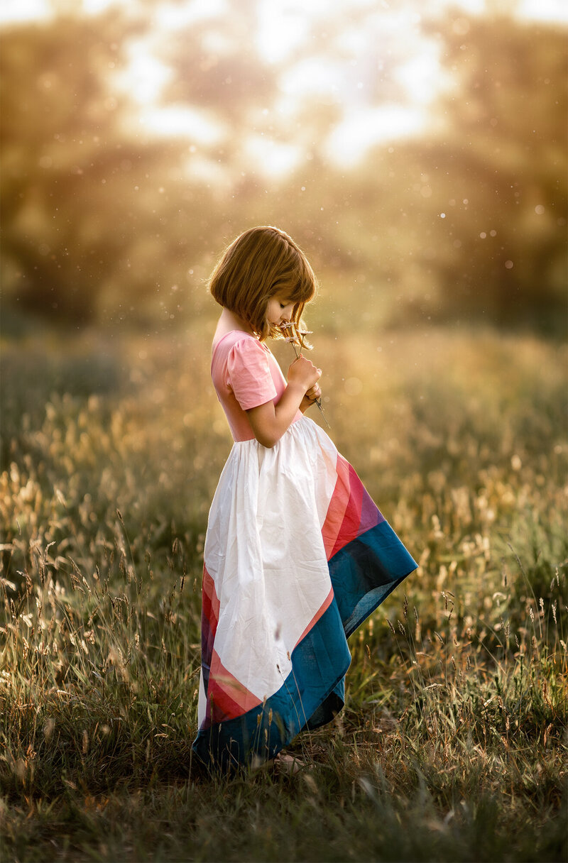 Little Girl Smelling Flowers In The Sunshine