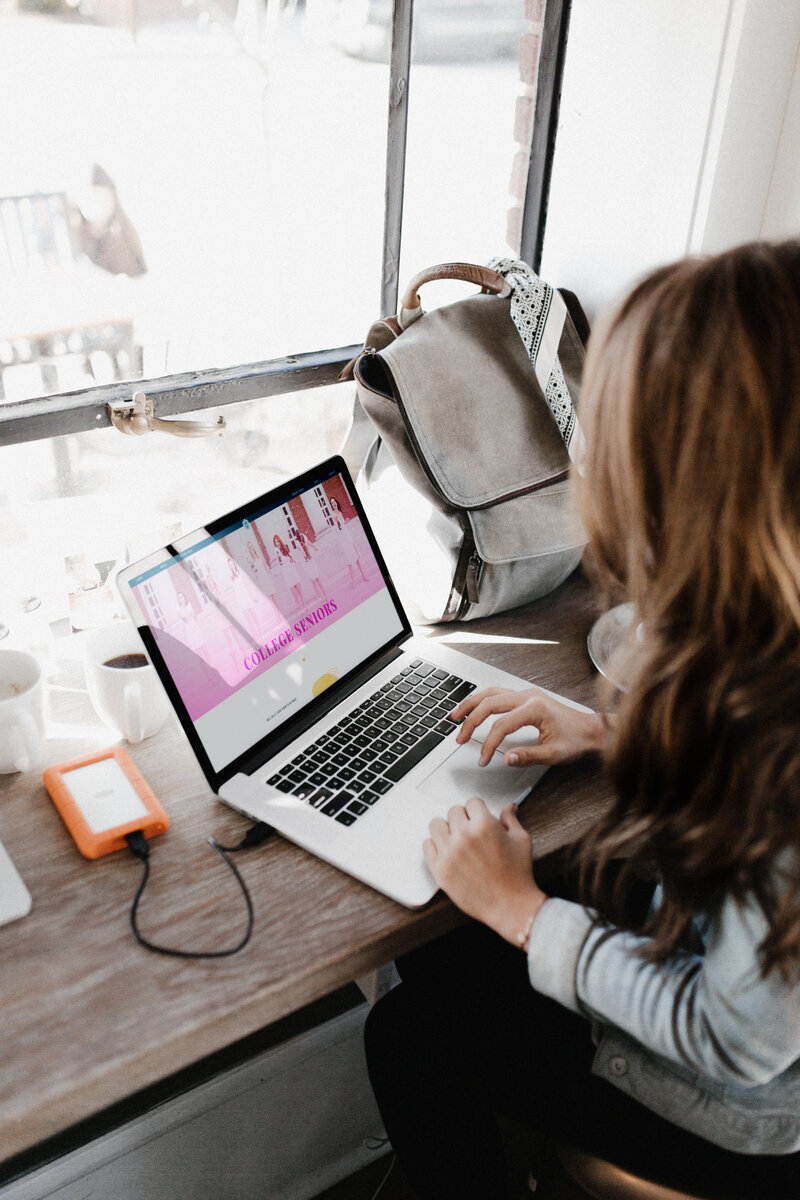 Girl scrolling on her laptop looking at a senior photographers website