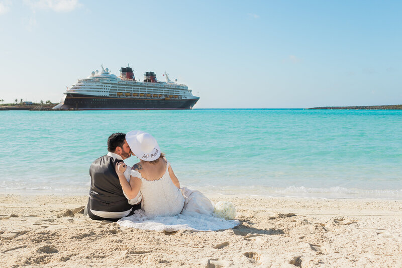 Couple kissing on beach with Disney Cruise ship in background