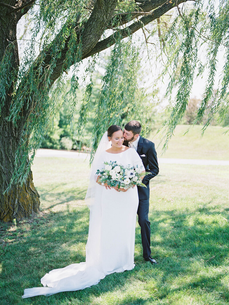 bride and groom embrace under a Willow tree photo by photographer in Grand Rapids, Michigan Cynthia Mae