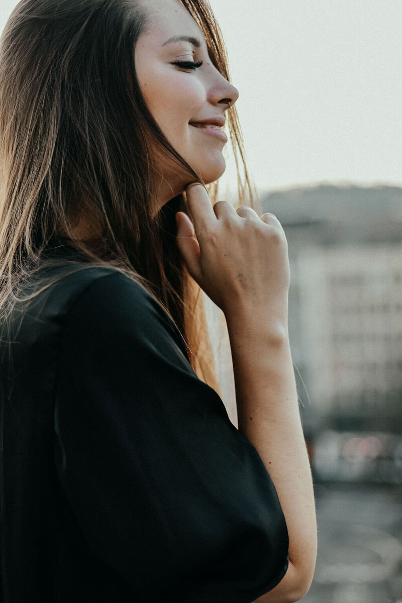 Profilportrait einer Frau mit Blick zur Seite im urbanen Umfeld

