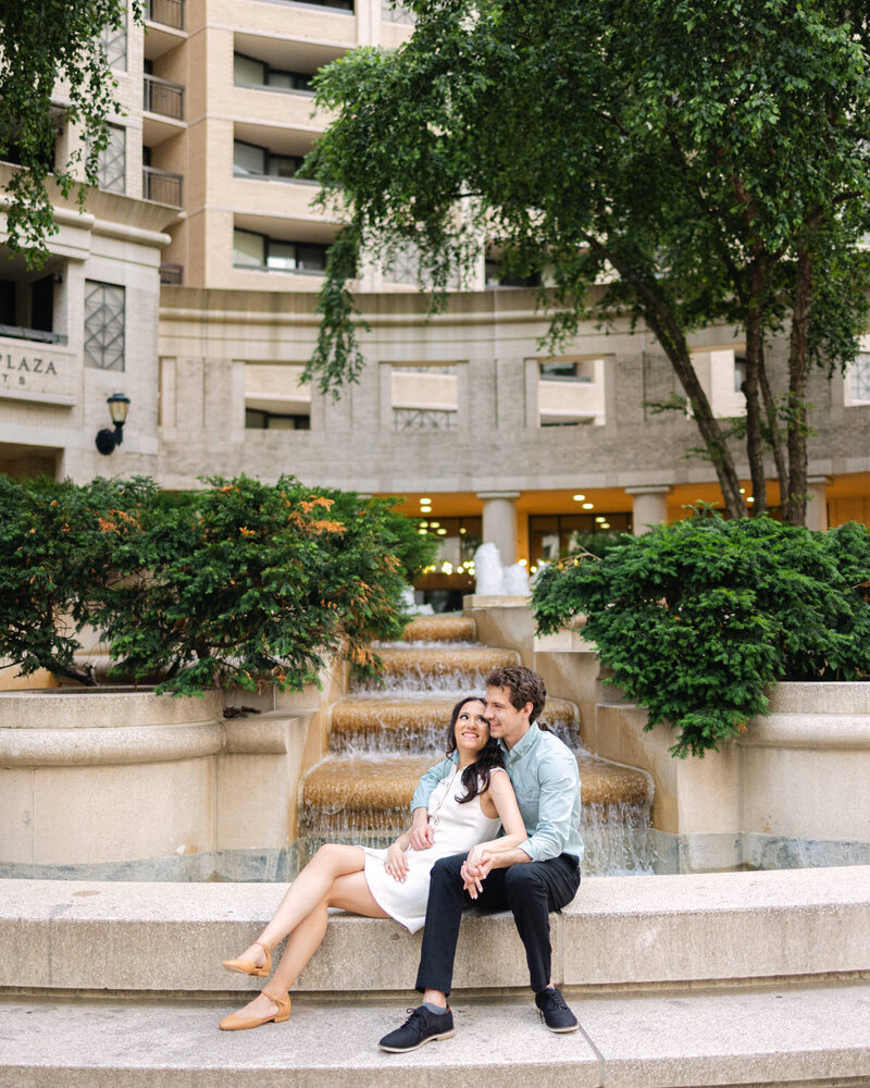 A couple posing after their wedding in their wedding attire and bouquet with a green stone wall in the background.