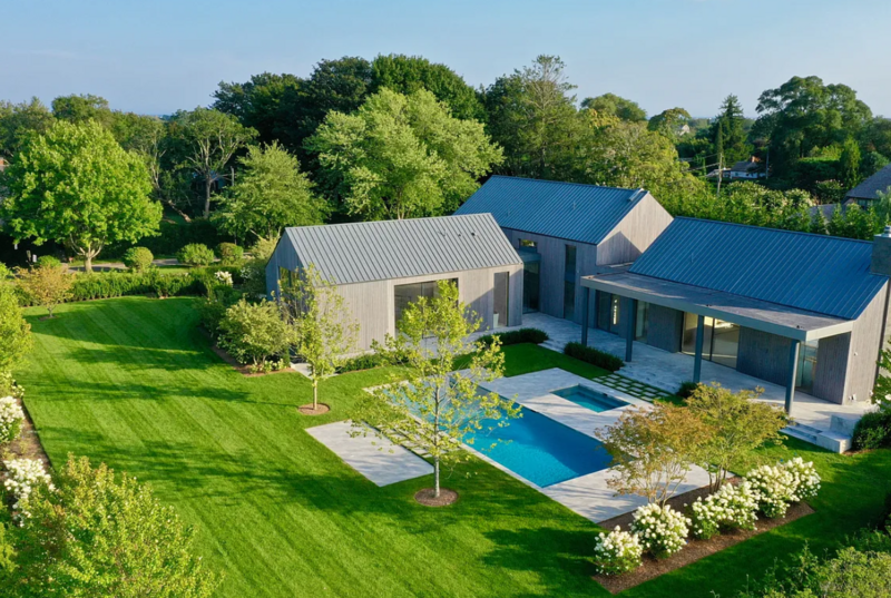 Black wood modern farmhouse venue rental featuring muskoka chairs and a pool