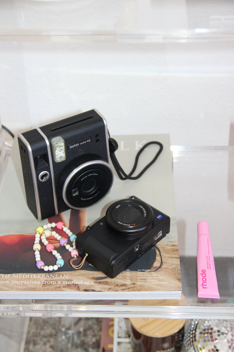 Aesthetic flat lay of a camera, Rhode lipstick, and creative tools for content creation and branding
