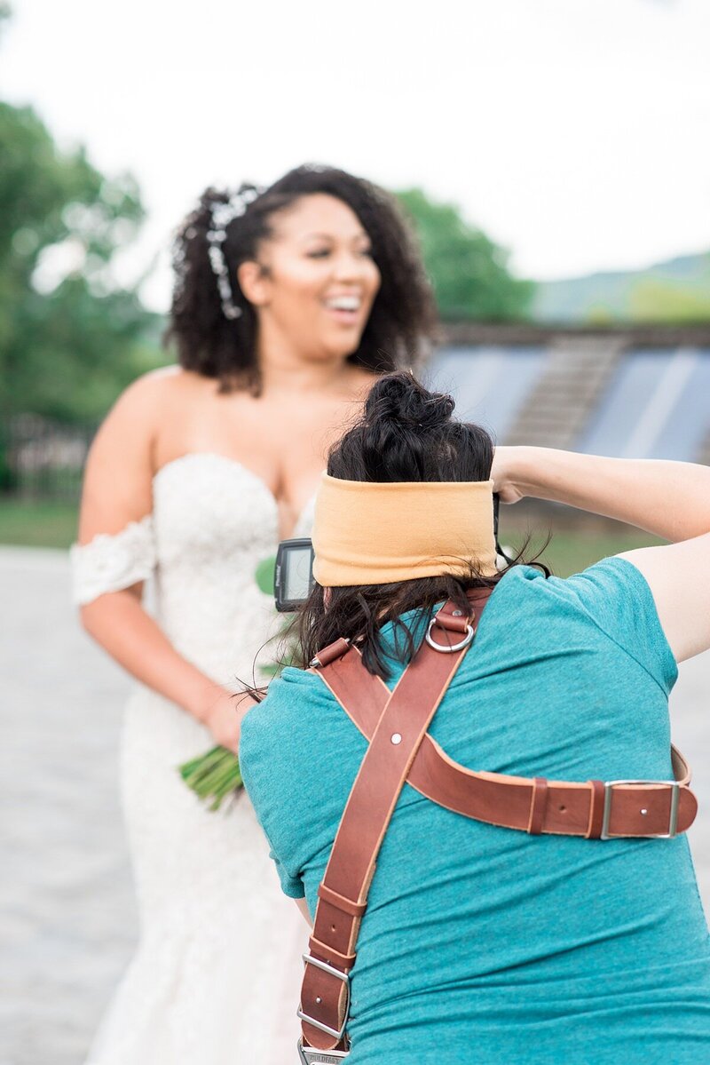Behind the scenes photo of photographer wearing a Holdfast camera strap and taking a photo of a bride