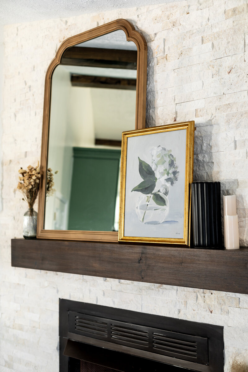 Custom built and stained fireplace mantel with mirror, frames and vases as decor.