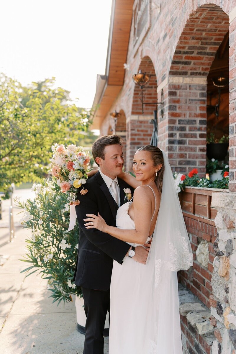 groom gazes affectionately at the bride while posing lovingly in front of the century room at grbic events in st. louis