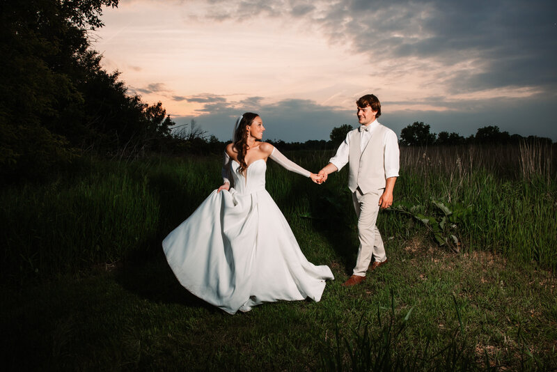 A bride and groom laugh while sitting on a stone garden bench cuddling captured by a Milwaukee Wedding Photographer