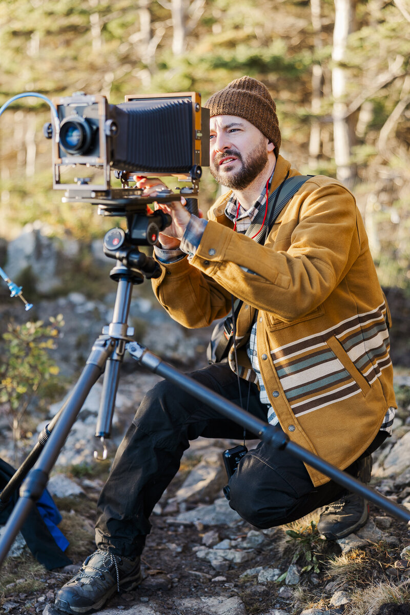 Kenneth laughing behind a large format film camera at an Acadia elopement