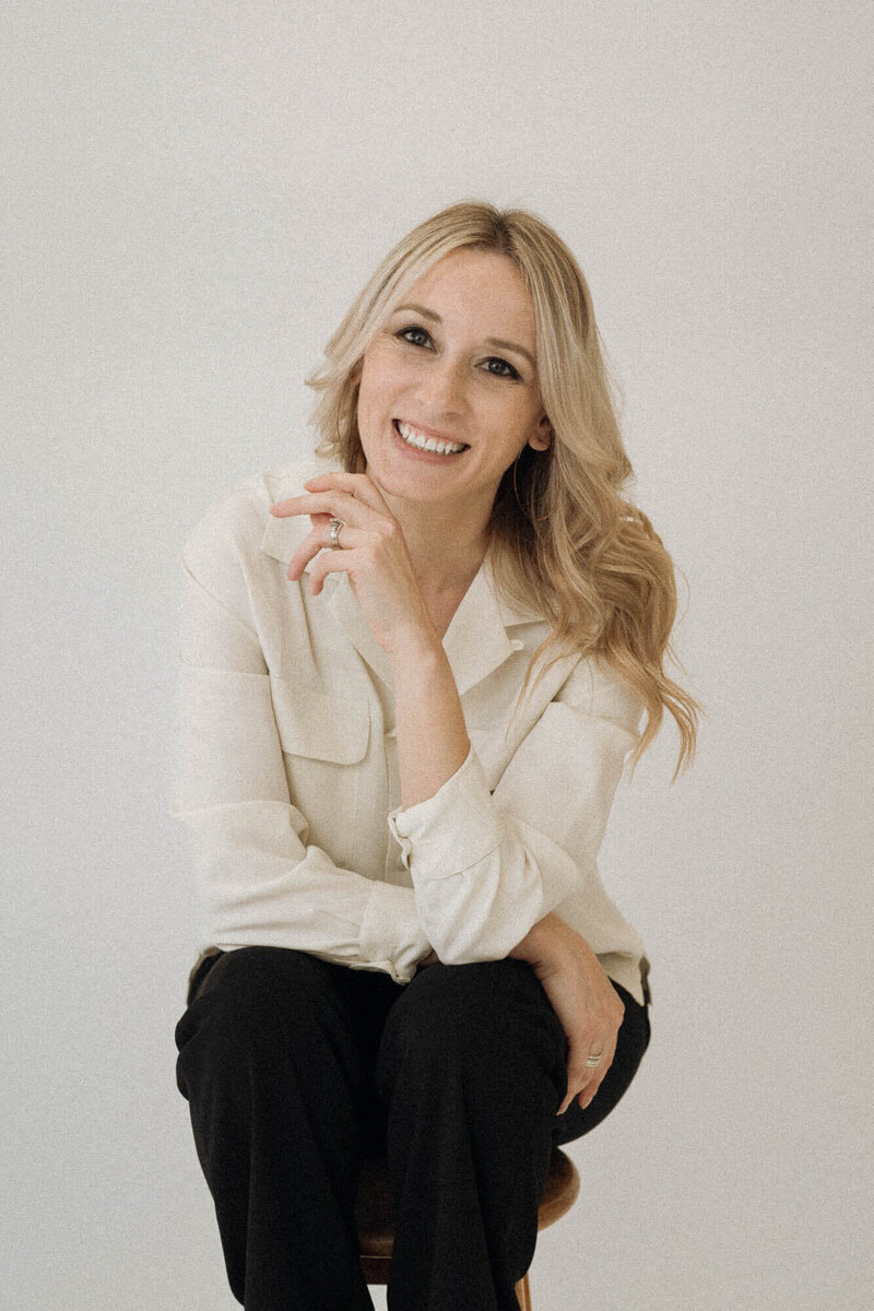 Professional branding portrait of Phoenix boudoir photographer Joy Steele, smiling confidently in natural light against a clean white background.