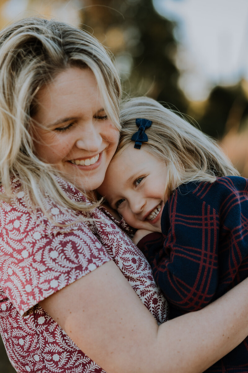 mother hugging her daughter tight and both smiling and giggling