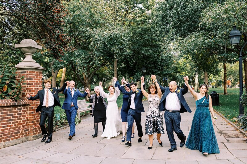 Wedding party waking hand in hand and cheering with bride and groom