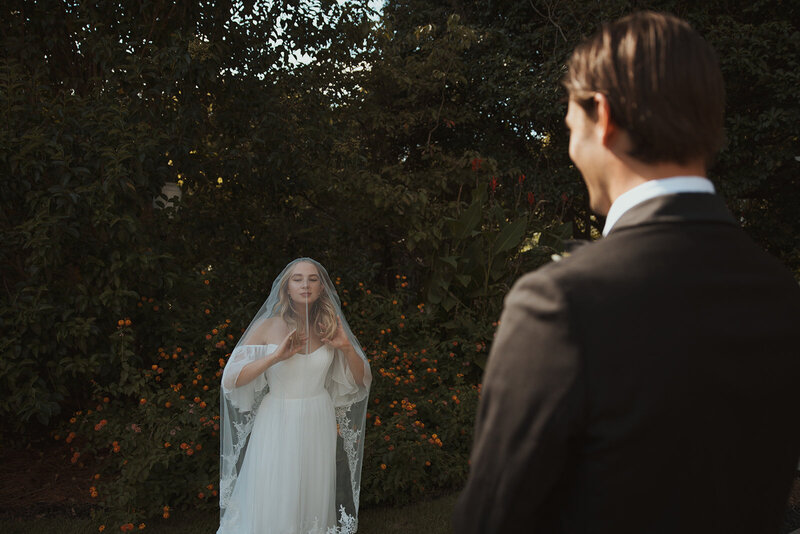 photograph of bride under veil with groom admiring her