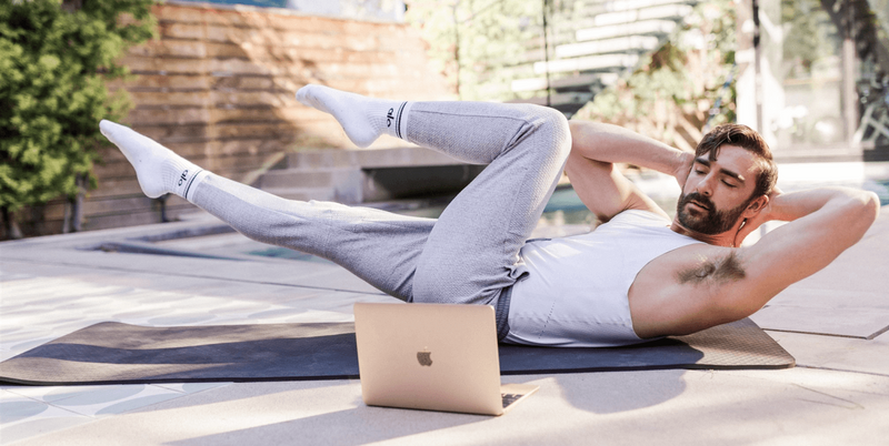 Man doing bicycle crunches while watching a laptop screen