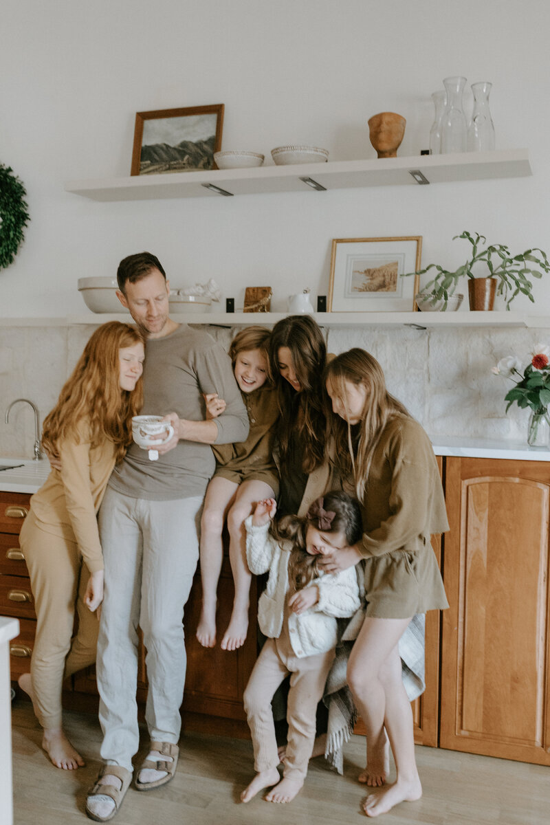 A family cuddles together and looks at each other in the kitchen in their Lafayette, Indiana home. 
