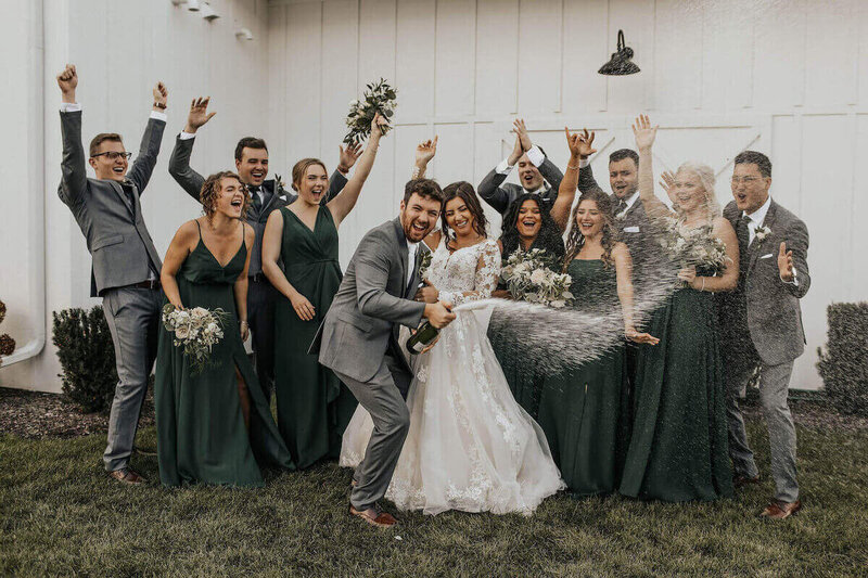 Bride and Groom with wedding party spraying champagne at Fete of Wales in Wisconsin by wedding planners in milwaukee.