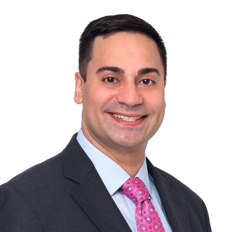 A man with a pink tie smiling and posing for his corporate headshot.