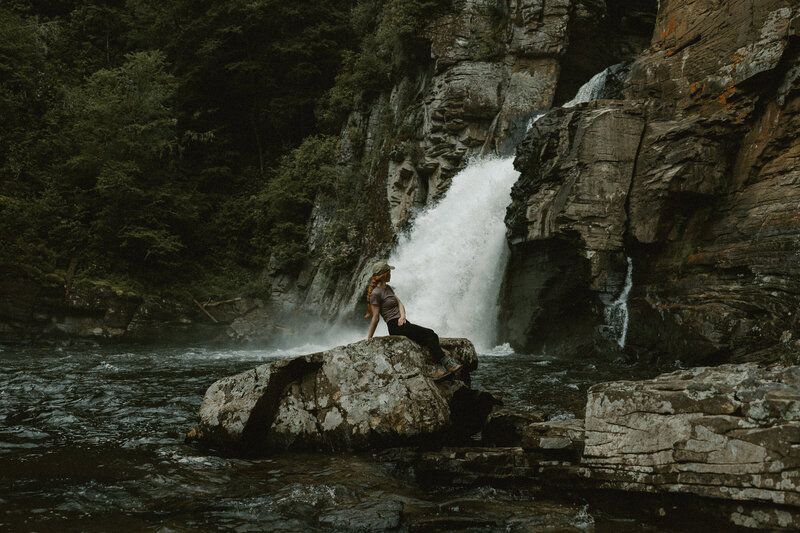 woman sitting on dead tree with mountains in background