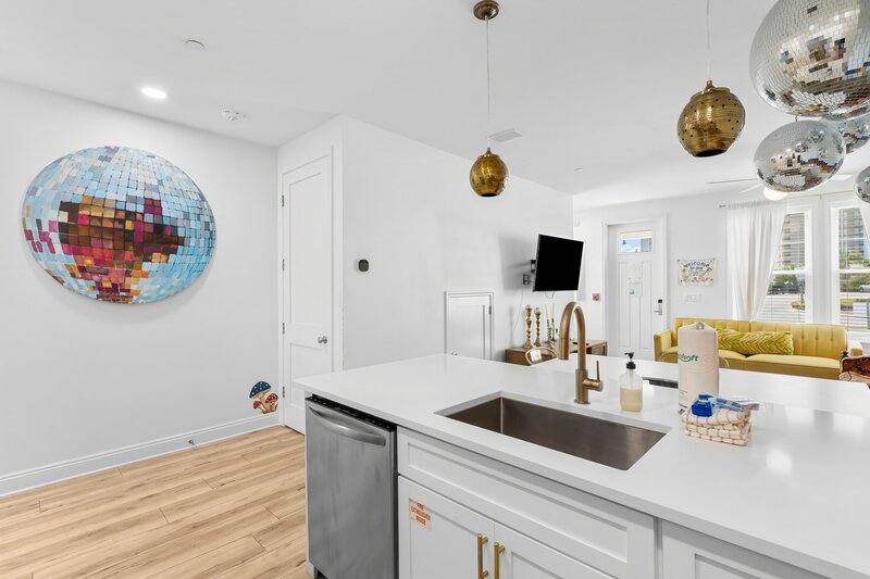 Open view of kitchen and living area with retro decor and unique disco ball art at Groovy Shack near Santa Rosa Beach and Panama City Beach