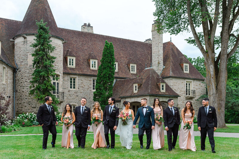 a bride and groom walking and laughing with their wedding party on the grounds of Eaton Hall captured by Ottawa wedding photographer JEMMAN Photography