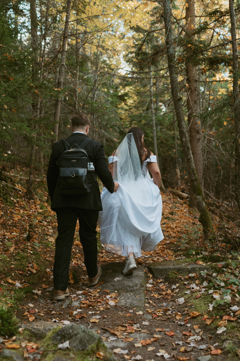 Bride and groom walking away amidst the foliage during their New Hampshire elopement.