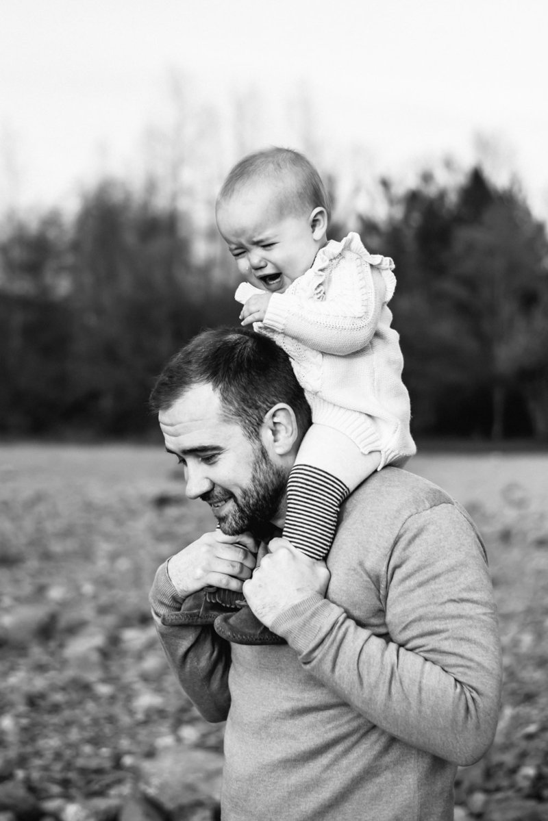 Toddler crying while being carried on dad's shoulders