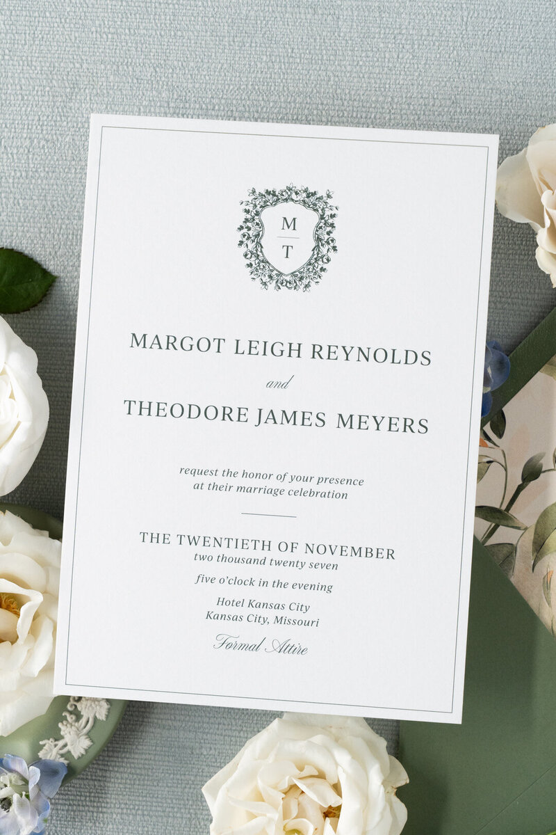 White curved menu card on a plate with a brown velvet napkin and flowers
