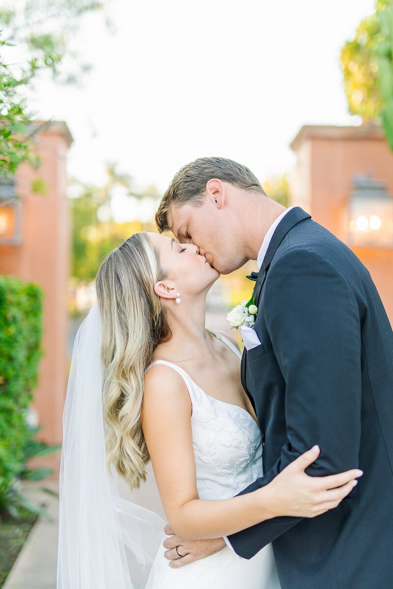 Newly married couple kissing at the gates at Rancho Valencia in Rancho Sante Fe, California.