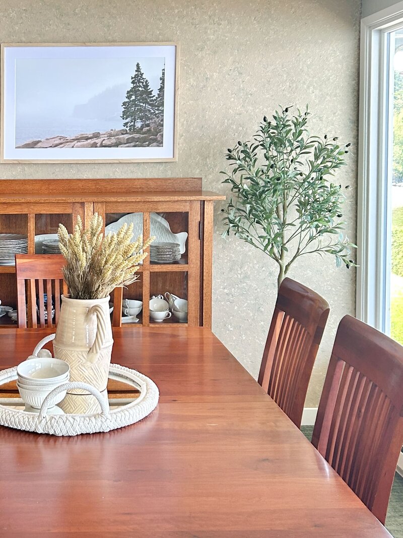 Dining room staged by Modern Mollusk in a Pacific Northwest waterfront home featuring wood furniture, neutral decor, and coastal artwork.