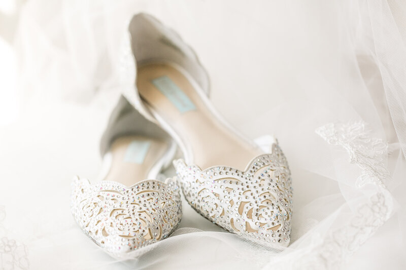 A pair of white jeweled flat shoes
