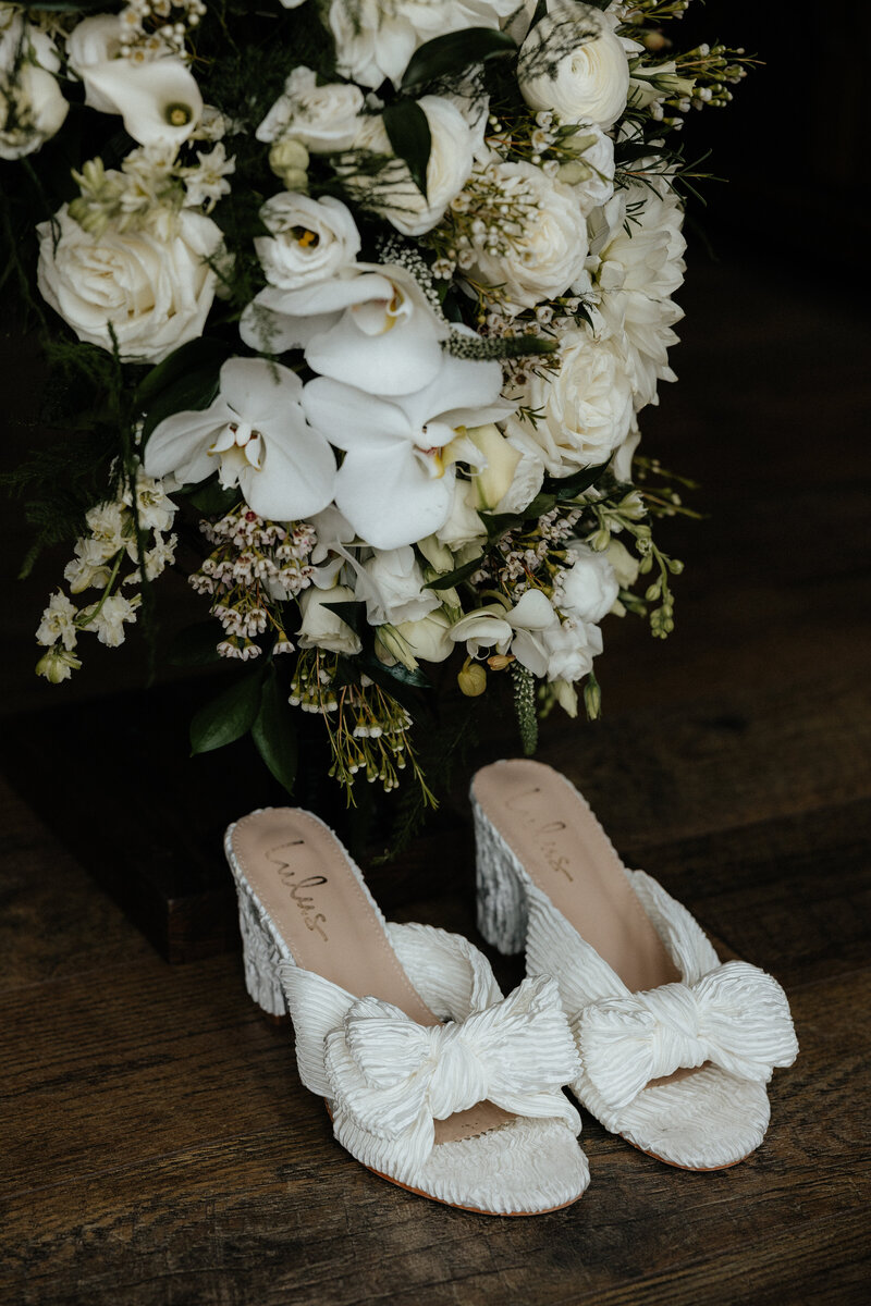 Bridal shoes in front of a bouquet.
