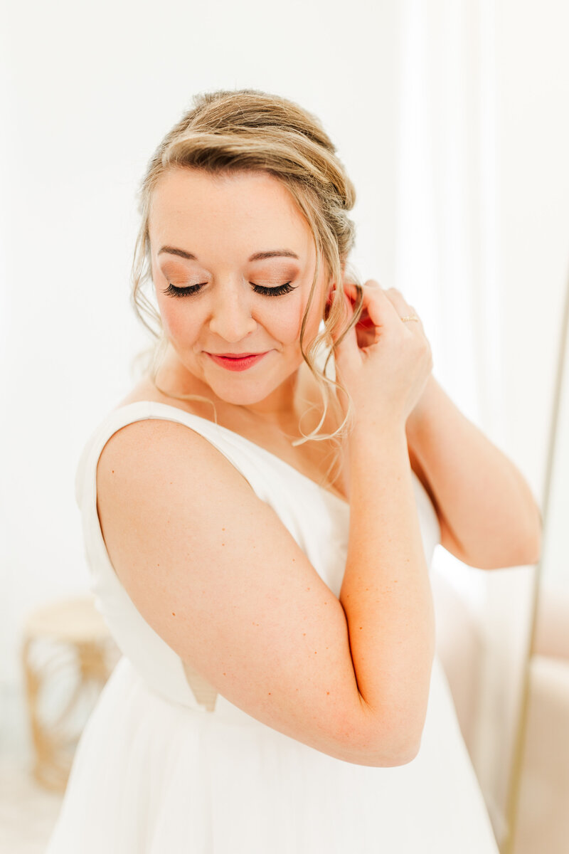 a bride putting on earrings